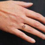 A gold ring with a pink tourmaline on the finger.